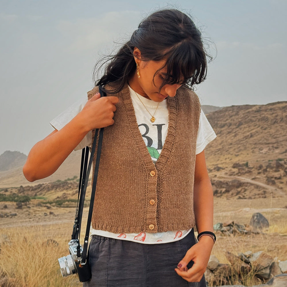 Person wearing a brown knitted wool vest in a desert landscape
