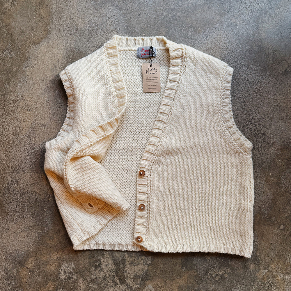 Beige knitted wool vest with buttons on a textured surface