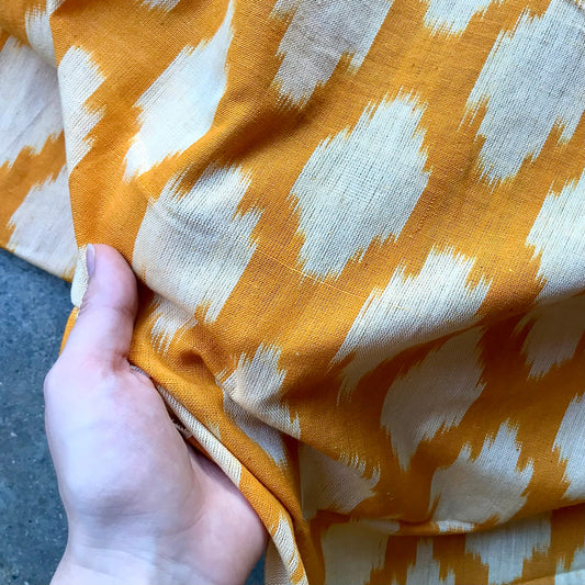 Ikat 495825 Folded fabric with orange and white pattern on a blue textured background