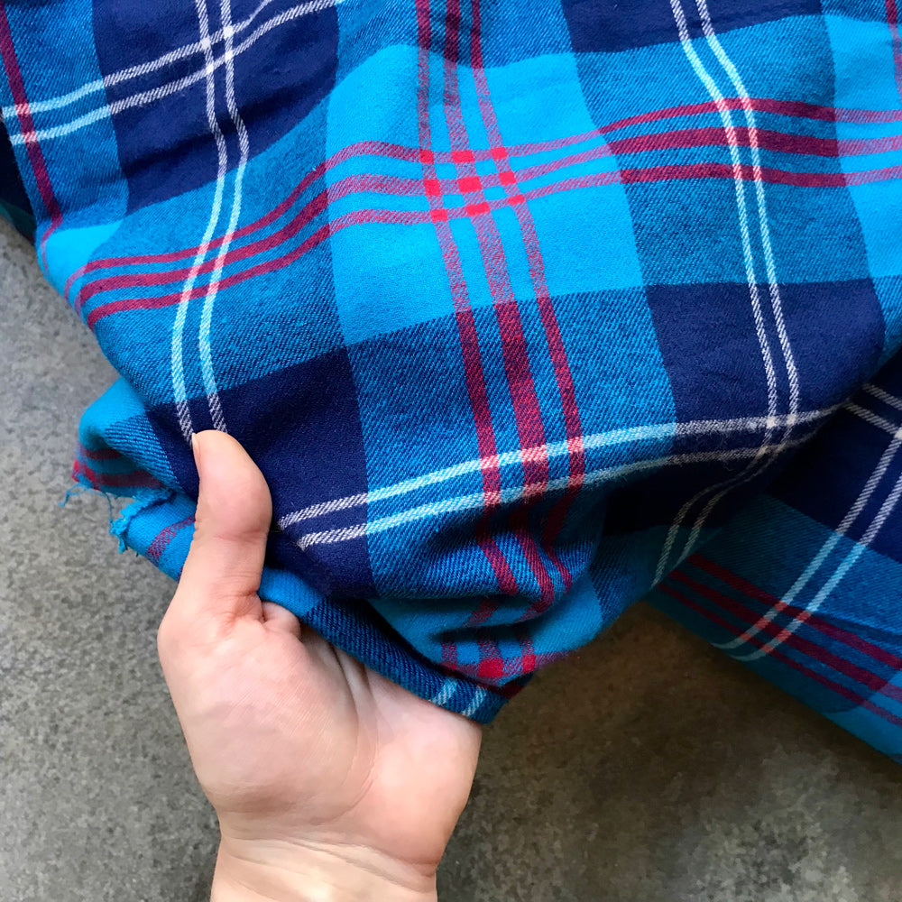 Tartan 41058521 - hand holding blue plaid fabric with red and white lines on a gray surface