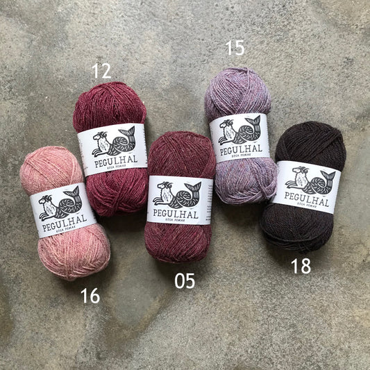 Four skeins of Pegulhal fingering weight portuguese wool yarn in shades of pink, purple and lilac.