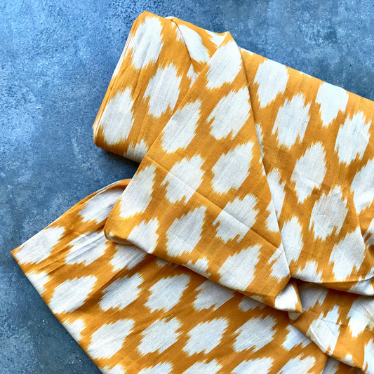 Ikat 495825 Folded fabric with orange and white pattern on a blue textured background