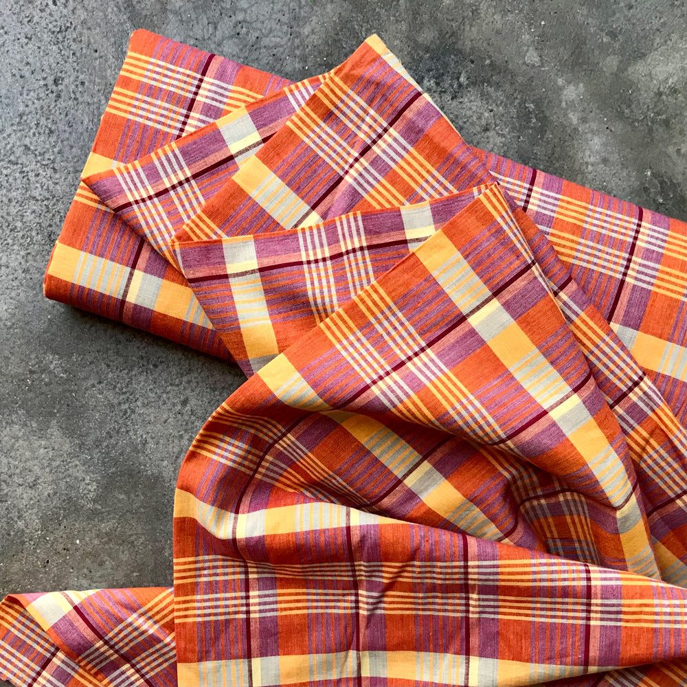 Madras 326125 - Plaid fabric with orange, red, and yellow pattern on a gray surface