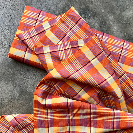 Madras 326125 - Plaid fabric with orange, red, and yellow pattern on a gray surface