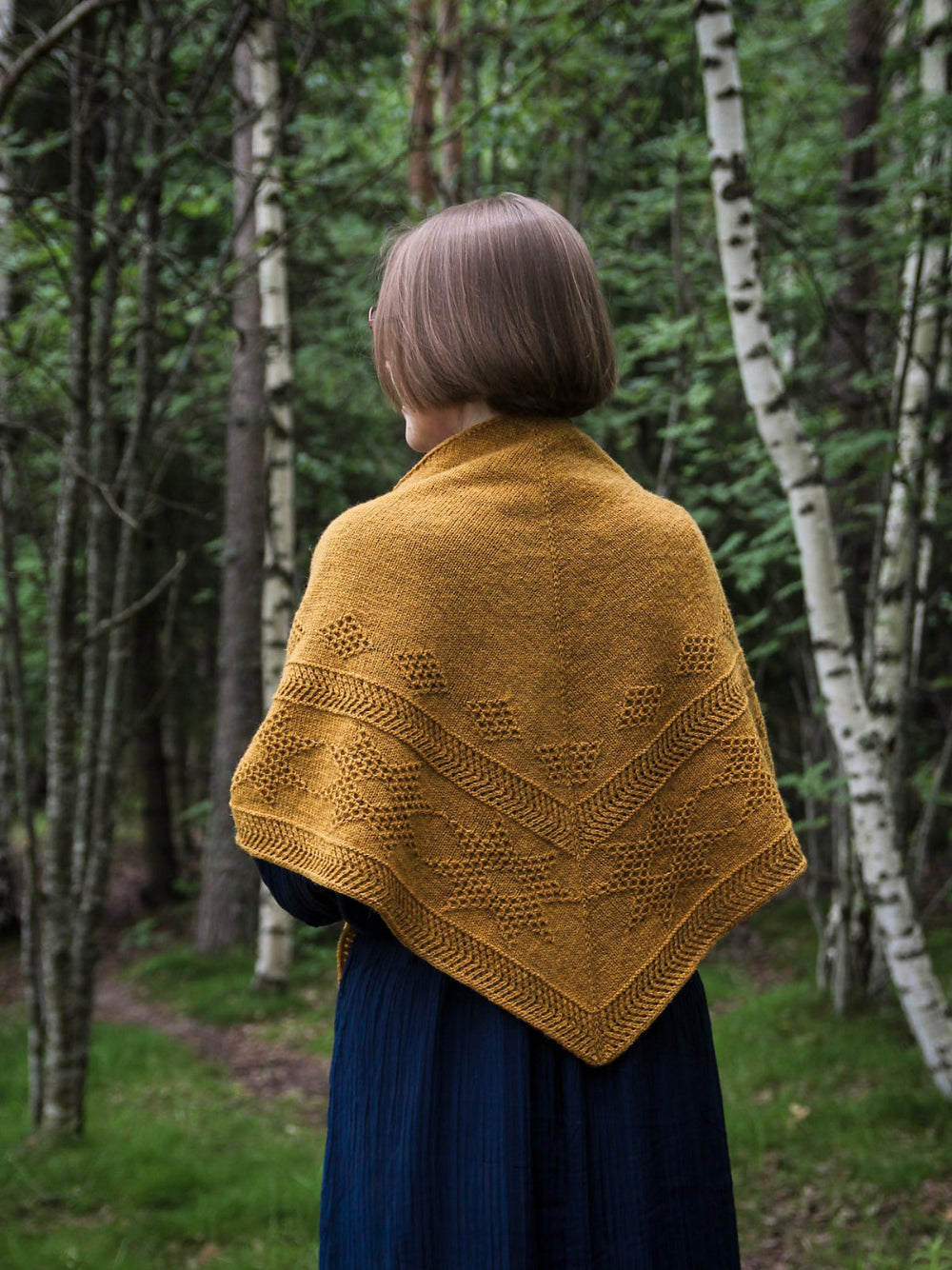 Oisin shawl in Mondim B580, featuring textured geometric patterns and a tassel detail.