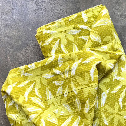 Mustar leaves: Yellow fabric with white leaf pattern on a gray surface