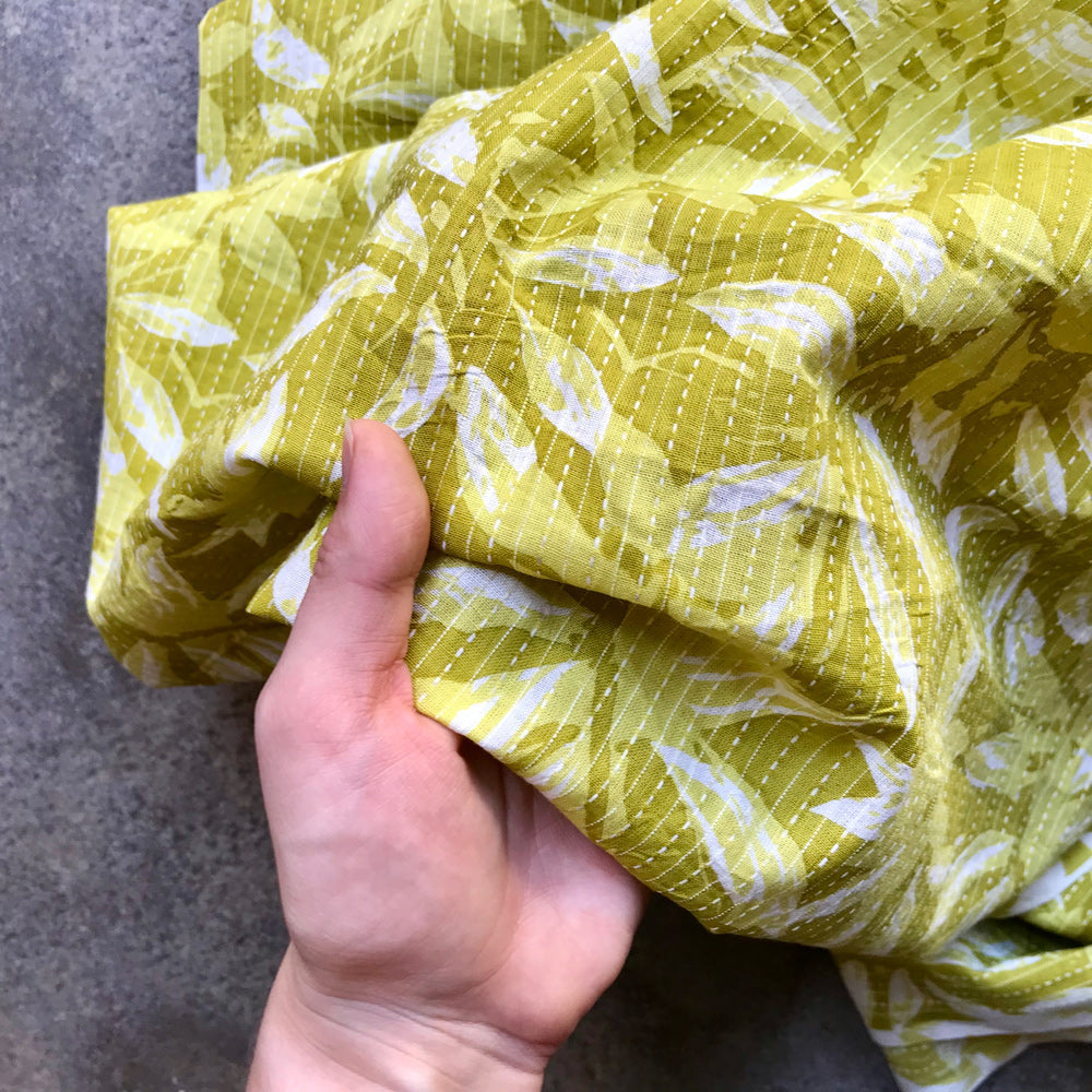 Mustard leaves Yellow fabric with white leaf pattern on a gray surface