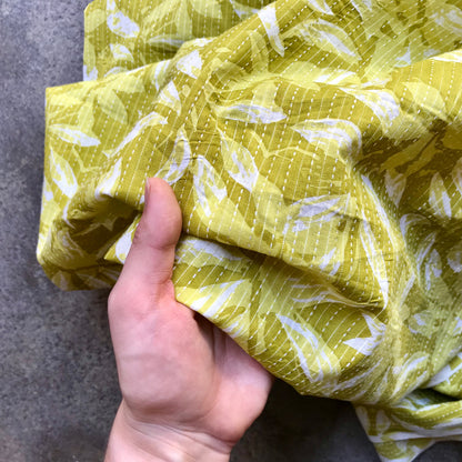 Mustard leaves Yellow fabric with white leaf pattern on a gray surface