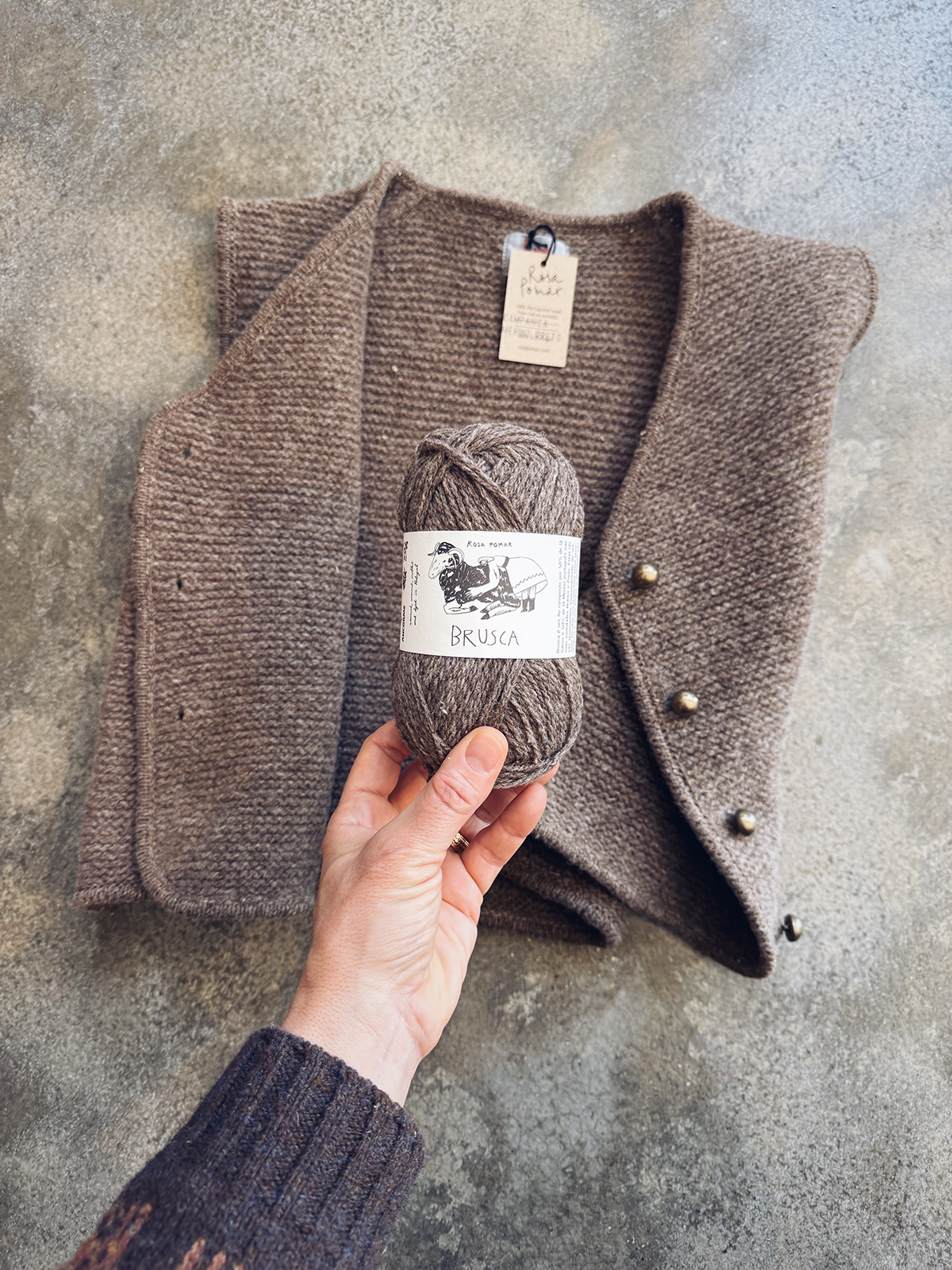 Brown knitted vest with a ball of yarn on a textured surface