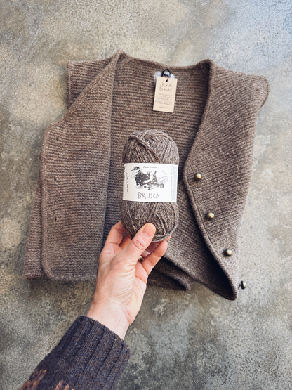 Brown knitted vest with a ball of yarn on a textured surface