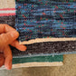 Close-up of a hand holding a piece of multicolored handwoven rag rug.