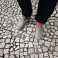 Person wearing wool felt clogs / sandals and colorful handknit socks on a stone pavement in Lisbon