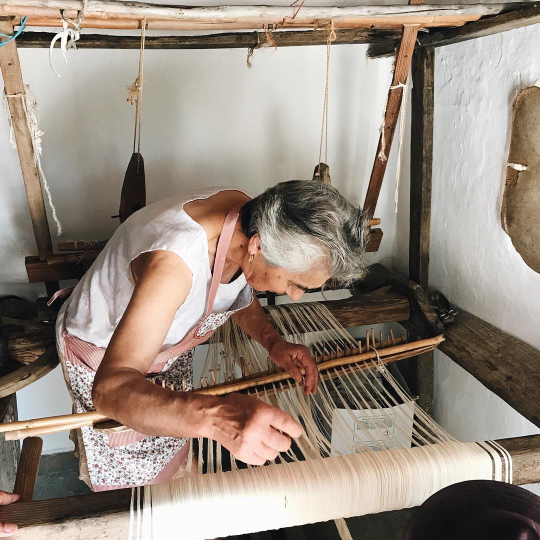 Woman weaving on a traditional loom in a rustic setting